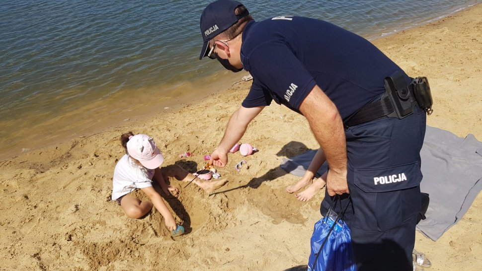 Na plaży nad Łysiną policjant wręcza dzieciom upominki