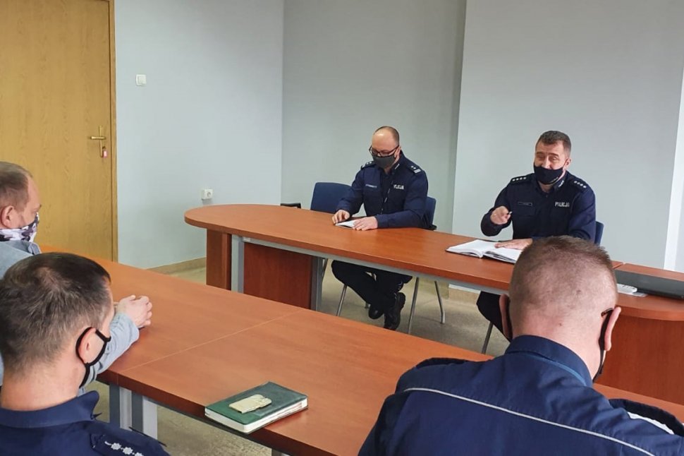 Na pierwszym planie policjanci siedzą tyłem. Na drugim planie Komendant i Zastępca Komendanta KPP Bieruń