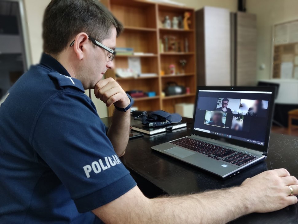 Policjant siedzi przy laptopie i prowadzi prelękcję online