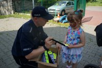 Policjant wręcza dziecku odblaski