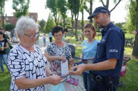Policjant i organizatorka festynu wręczają ulotki jego uczestnikom