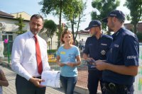 Policjanci i organizatorka festynu wręczają ulotki Burmistrzowi Miasta Bieruń