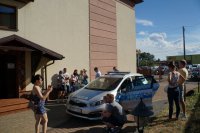 Radiowóz policyjny i dzieci z rodzicami przy żłobku