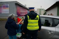 Policjant i dzieci podczas akcji &quot;Bezpieczna rodzina na drodze&quot; w Lędzinach