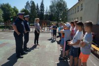 W lewej części zdjęcia stoją policjanci i nauczycielka, po prawej stronie stoją dzieci