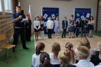 Policjant i uczniowie na sali gimnastycznej podczas uroczystego apelu z okazji rozpoczęcia roku szkolnego