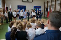 Policjant i uczniowie na sali gimnastycznej podczas uroczystego apelu z okazji rozpoczęcia roku szkolnego