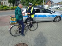 Mężczyzna na rowerze stoi przy policjancie. Na drugim planie radiowóz