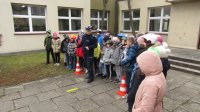 Policjant i grupa dzieci stoją przy szkole