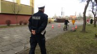 Policjant egzaminuje ucznia, który jedzie na rowerze