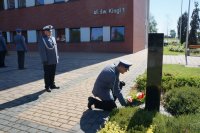 Komendant Powiatowy Policji w BIeruniu składa wieniec pod obeliskiem. Na drugim planie stoi Naczelnik Wydziału Ruchu Drogowego