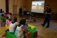 Policjanci podczas prelekcji (na drugim planie). Na pierwszym planie dzieci siedzą na pufach