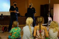 Policjanci podczas prelekcji (na drugim planie). Na pierwszym planie dzieci siedzą na pufach