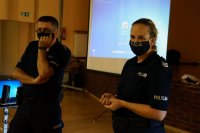 Policjanci w maseczkach podczas prelekcji, w tle ekran