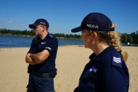 Policjanci stoją na plaży na Łysinie, w tle widać zalew