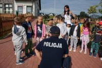 Policjant przeprowadza pogadankę z grupą dzieci