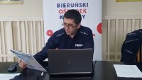 Policjant siedzi przy laptopie, prowadzi zdalną prelekcję