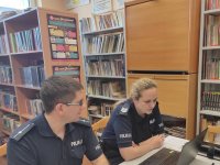 policjant i policjantka prowadzą profilaktykę przez komputer z uczniami szkoły podstawowej nr 2 w ledzinach