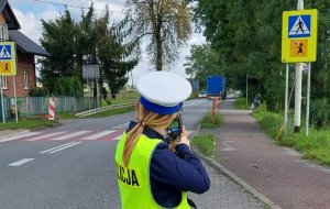 Policjantka ruchu drogowego w rejonie przejścia dla pieszych dokonuje pomiaru prędkości pojazdów
