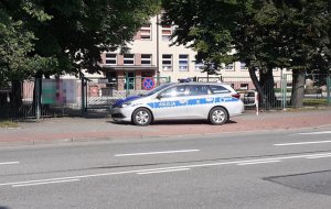 Policyjny radiowóz stoi w rejonie szkoły. Na pierwszym planie widać jezdnię