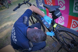 Strażnik miejski kuca przy rowerze znakując go