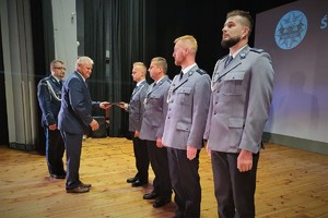 Na scenie Starosta Bieruńsko-Lędziński w asyście Komendanta Powiatowego Policji w Bieruniu wręcza wyróżnienia policjantom stojącym w rzędzie na baczność