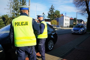 Policjanci ruchu drogowego stoją przy kontrolowanym samochodzie
