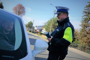 Policjant ruchu drogowego rozmawia z kierowcą zatrzymanego do kontroli pojazdu. Mężczyźni uśmiechają się do siebie