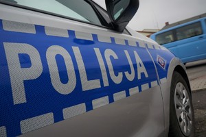 Zdjęcie przedstawia fragment radiowozu z napisem POLICJA