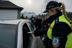 Zdjęcie: policjantka i dzieci wręczają kierowcy gadżety