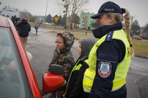 Zdjęcie: policjantka i dzieci wręczają kierowcy gadżety