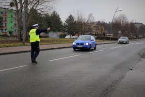 Zdjęcie: policjant ruchu drogowego stoi na jezdni, zatrzymuje do kontroli pojazd