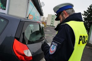 Zdjęcie: Policjant ruchu drogowego stoi przy samochodzie zatrzymanym do kontroli