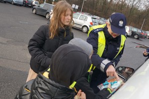 Zdjęcie: policjantka i dzieci wręczają kierowcy gadżety