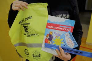 Zdjęcie: zbliżenie na trzymane przez policjantkę przedmioty profilaktyczne
