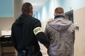 Na zdjęciu widać policjanta wraz z zatrzymanym