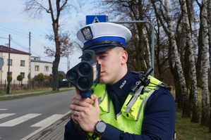 Na zdjęciu widać policjanta mierzącego prędkość w rejonie przejścia dla pieszych