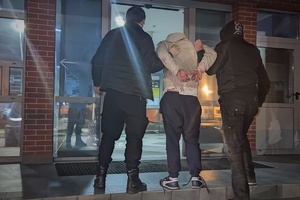 Na zdjęciu widać policjantów prowadzących zatrzymanego