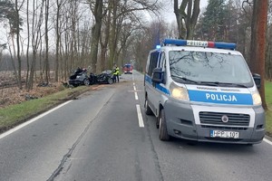 Na zdjęciu widzimy radiowóz policyjny, policjantów oraz rozbite auto