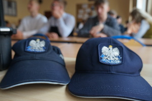 Na zdjęciu widzimy czapki policyjne oraz uczniów w czasie pogadanki