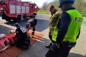 Na zdjęciu widzimy policjanta, strażaka pożarnego oraz ratownika medycznego w czasie wykonywania zadania przez kierującego, który popełnił wykroczenie