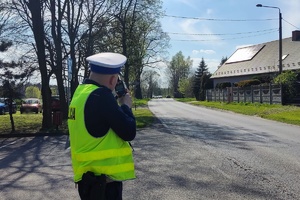 Na zdjęciu widzimy policjanta mierzącego prędkość nadjeżdżających pojazdów