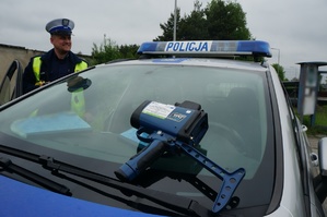 Na zdjęciu widzimy policjanta oraz radiowóz