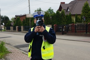 Na zdjęciu widzimy policjanta, który dokonuje pomiaru prędkości pojazdów