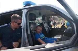 Na zdjęciu widzimy policjanta przy radiowozie w czasie Dnia Dziecka