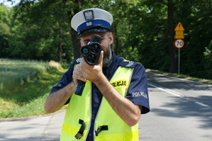 Na zdjęciu widzimy policjanta w czasie sprawdzania prędkości pojazdów