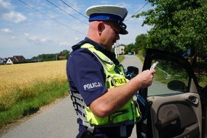 Na zdjęciu widzimy policjanta w czasie przeprowadzania kontroli pojazdu