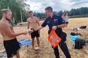 Na zdjęciu widzimy policjanta rozmawiającego z plażowiczami