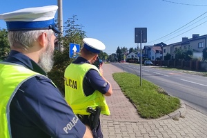 Na zdjęciu widzimy policjantów w czasie mierzenia prędkości w rejonie przejścia dla pieszych oraz szkoły