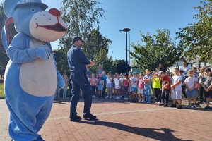 Na zdjęciu widzimy policjanta oraz sznupka wraz z grupą dzieci z przedszkola